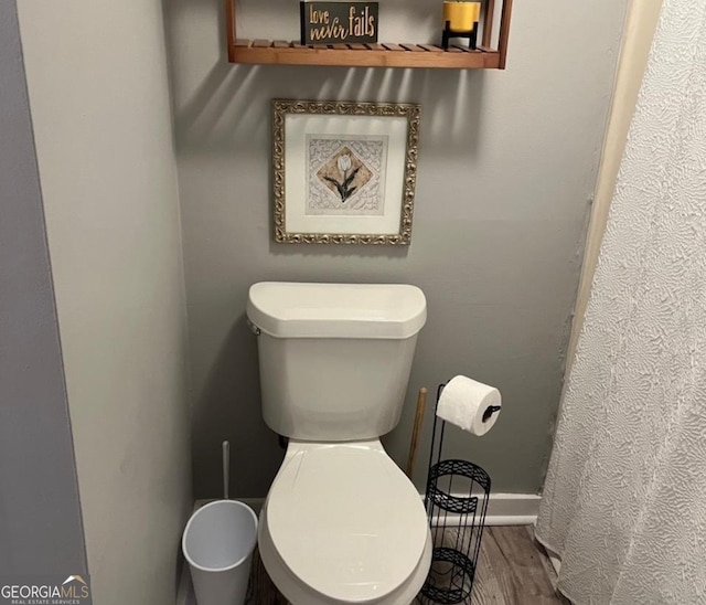 full bath featuring baseboards, wood finished floors, and toilet
