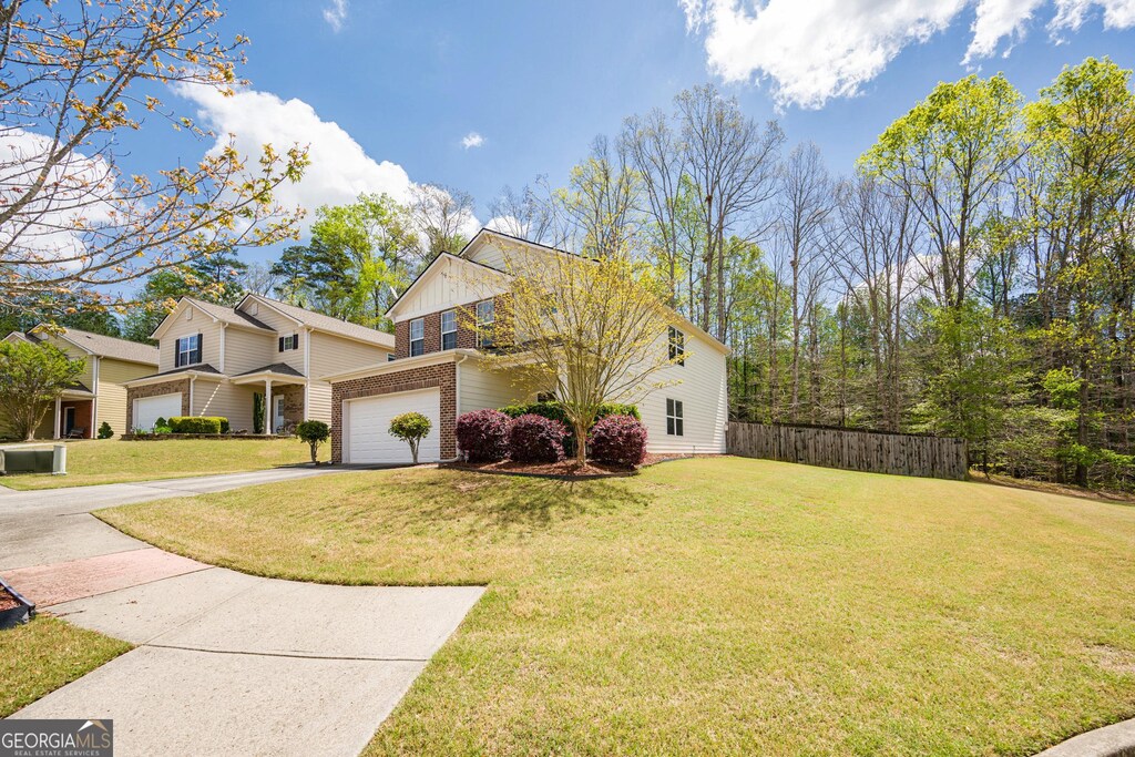 6884 Barker Station Walk, Sugar Hill, GA 30518 - view of front of home with fence, a front lawn, brick siding, an attached garage, and driveway
