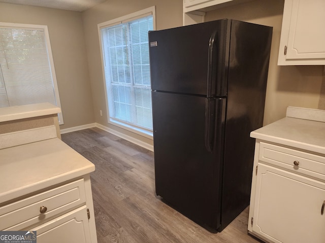 kitchen featuring light countertops, white cabinetry, freestanding refrigerator, and wood finished floors