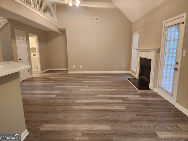 unfurnished living room featuring high vaulted ceiling, a high end fireplace, and baseboards