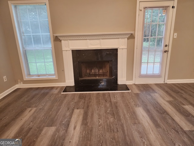 unfurnished living room with baseboards, wood finished floors, and a premium fireplace