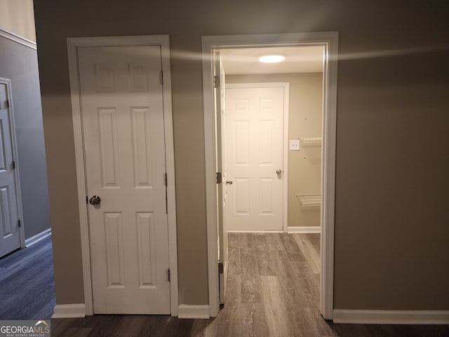 corridor with dark wood-type flooring and baseboards