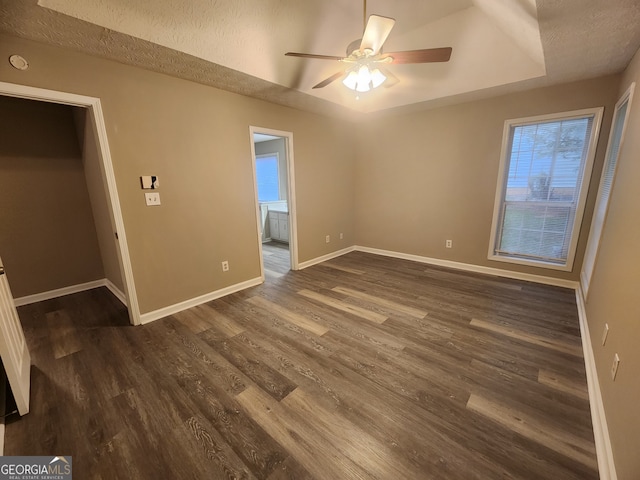 interior space featuring dark wood-style flooring, baseboards, ensuite bathroom, a textured ceiling, and a ceiling fan