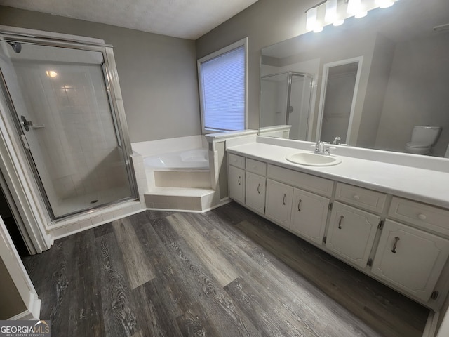 bathroom featuring vanity, a garden tub, a stall shower, and wood finished floors