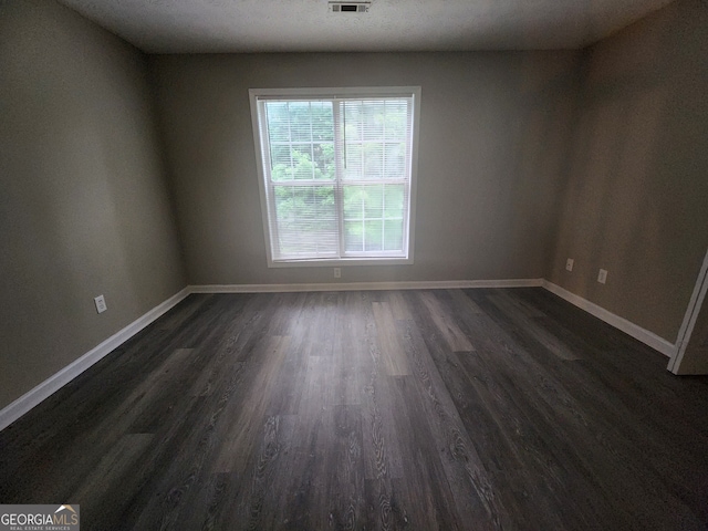 spare room with dark wood-type flooring, baseboards, and visible vents