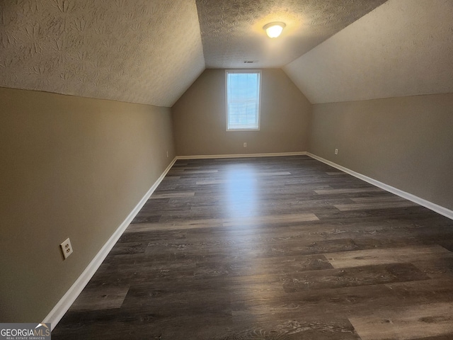 additional living space with a textured ceiling, dark wood-style flooring, and baseboards