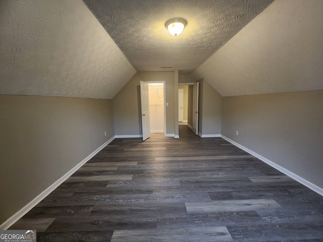 bonus room with dark wood finished floors, lofted ceiling, baseboards, and a textured ceiling