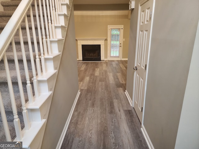hallway featuring baseboards, stairs, and dark wood-style floors