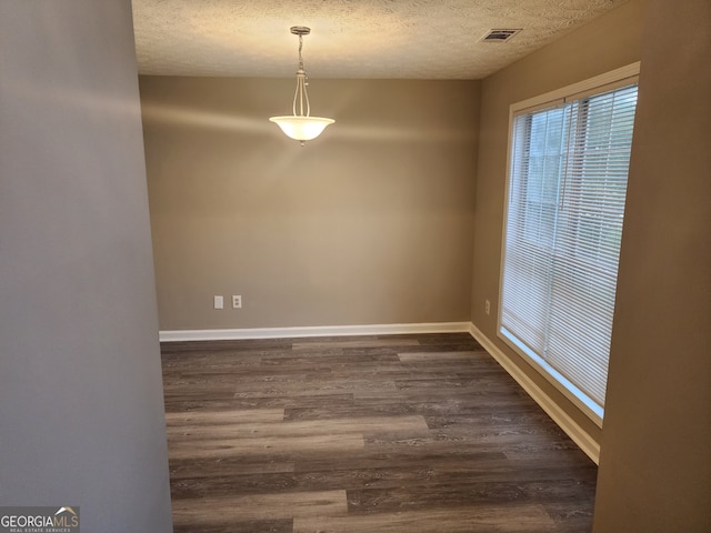 unfurnished dining area featuring visible vents, baseboards, dark wood-style floors, and a textured ceiling