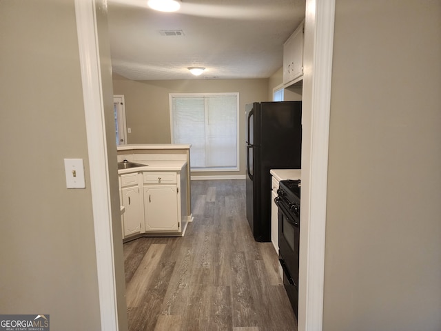kitchen with visible vents, white cabinets, a peninsula, black appliances, and dark wood-type flooring