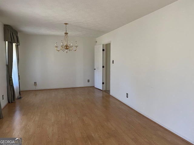 3021 Tiffin Cir, Macon, GA 31204 - empty room featuring light wood finished floors, baseboards, a textured ceiling, and a chandelier