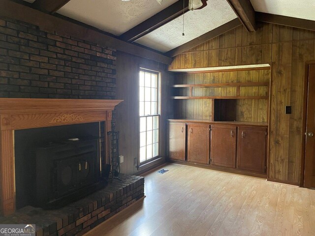 3021 Tiffin Cir, Macon, GA 31204 - unfurnished living room with a fireplace with raised hearth, light wood-type flooring, visible vents, and lofted ceiling with beams