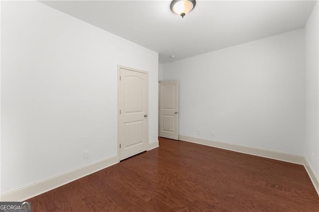 empty room with baseboards and dark wood finished floors