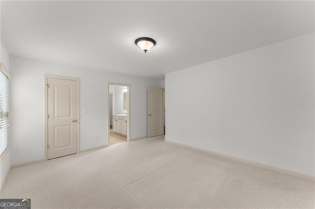 unfurnished bedroom with ensuite bathroom, baseboards, multiple windows, and light carpet
