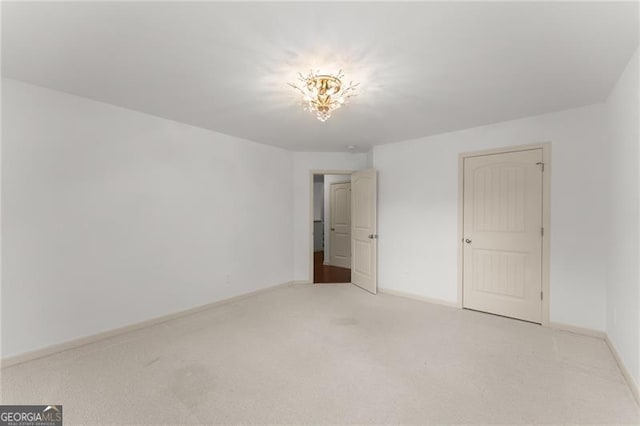 unfurnished bedroom featuring light carpet, a notable chandelier, and baseboards