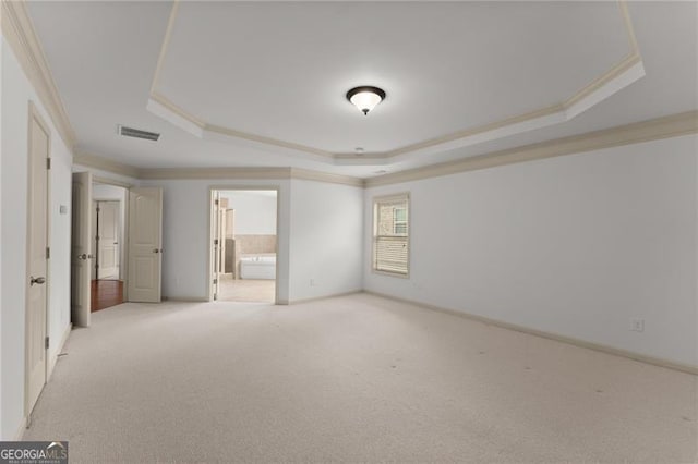 unfurnished bedroom featuring ensuite bath, crown molding, visible vents, a tray ceiling, and light colored carpet