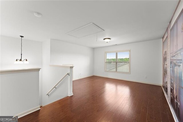 unfurnished living room featuring baseboards, attic access, and dark wood-style floors
