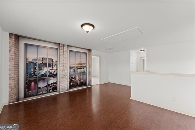 spare room with baseboards, attic access, and dark wood-style floors