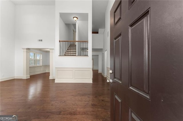 foyer entrance featuring dark wood-type flooring, a high ceiling, visible vents, and stairs