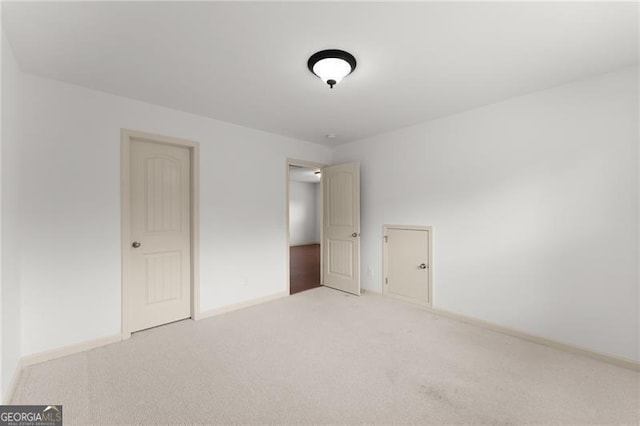 unfurnished bedroom with light colored carpet and baseboards