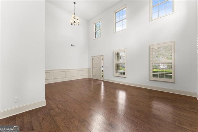 foyer with baseboards, high vaulted ceiling, a notable chandelier, and wood finished floors