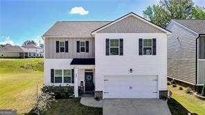 traditional home with a front yard, an attached garage, and driveway
