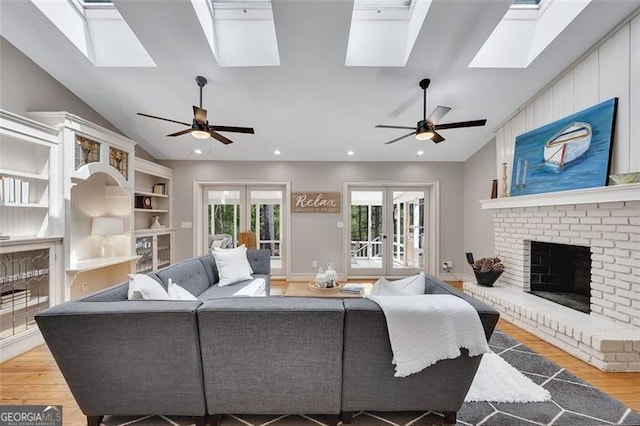 934 Pine Cir, Woodstock, GA 30189 - living area with vaulted ceiling with skylight, a brick fireplace, ceiling fan, wood finished floors, and french doors
