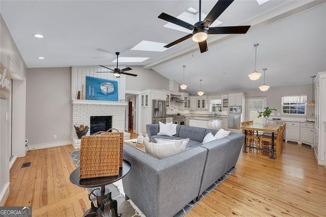 934 Pine Cir, Woodstock, GA 30189 - living area featuring a ceiling fan, a fireplace, recessed lighting, light wood finished floors, and lofted ceiling with skylight