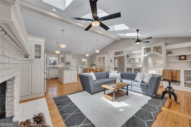 934 Pine Cir, Woodstock, GA 30189 - living area with a brick fireplace, light wood-type flooring, a ceiling fan, and lofted ceiling with skylight