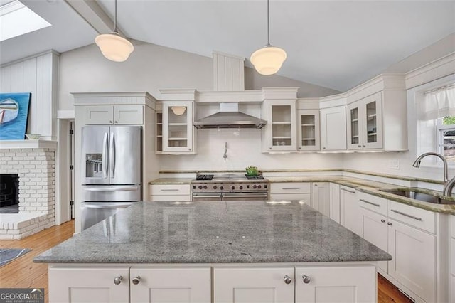 934 Pine Cir, Woodstock, GA 30189 - kitchen with a sink, wall chimney range hood, lofted ceiling with skylight, wood finished floors, and stainless steel appliances