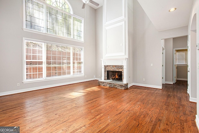4609 Mctyre Way NW, Marietta, GA 30064 - unfurnished living room with a ceiling fan, a towering ceiling, a stone fireplace, and wood finished floors