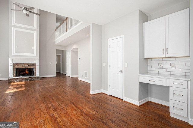 4609 Mctyre Way NW, Marietta, GA 30064 - unfurnished living room featuring built in study area, ceiling fan, dark wood-style flooring, arched walkways, and a fireplace