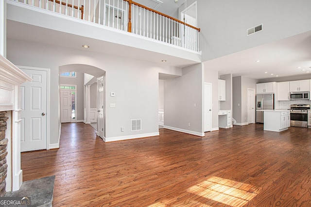 4609 Mctyre Way NW, Marietta, GA 30064 - unfurnished living room featuring a high ceiling, arched walkways, dark wood-type flooring, a fireplace, and recessed lighting