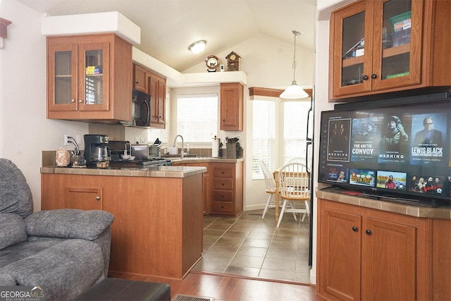 kitchen featuring lofted ceiling, black microwave, glass insert cabinets, open floor plan, and brown cabinets