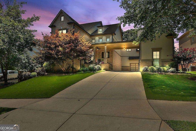 view of front of home featuring covered porch, concrete driveway, a front yard, and brick siding