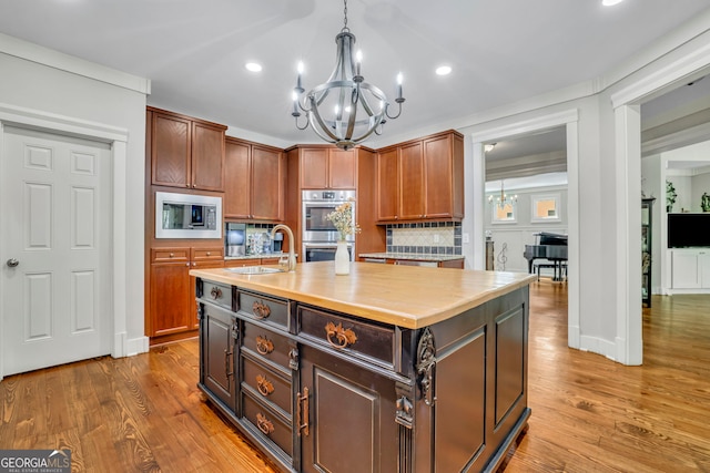 kitchen featuring a notable chandelier, light countertops, stainless steel appliances, wood finished floors, and backsplash