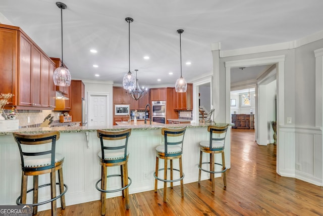 kitchen featuring decorative backsplash, a peninsula, light stone countertops, double oven, and built in microwave