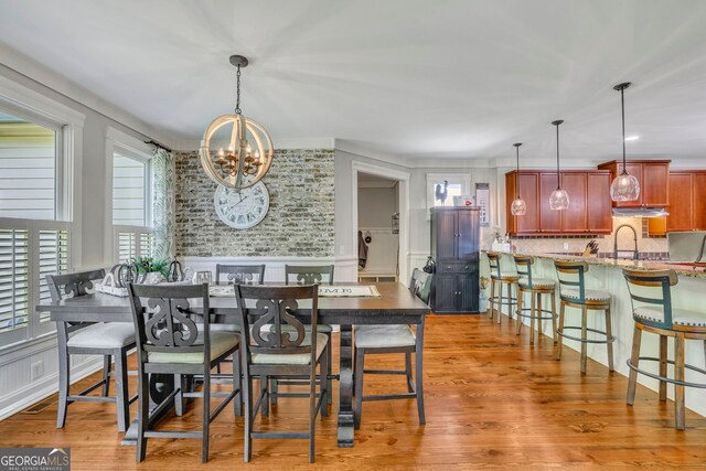 dining room with an inviting chandelier, wainscoting, a decorative wall, and light wood-type flooring