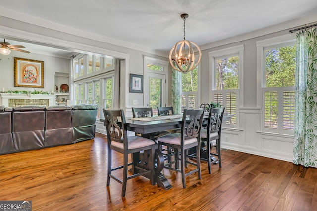 dining area featuring a fireplace, a decorative wall, a wealth of natural light, and hardwood / wood-style flooring