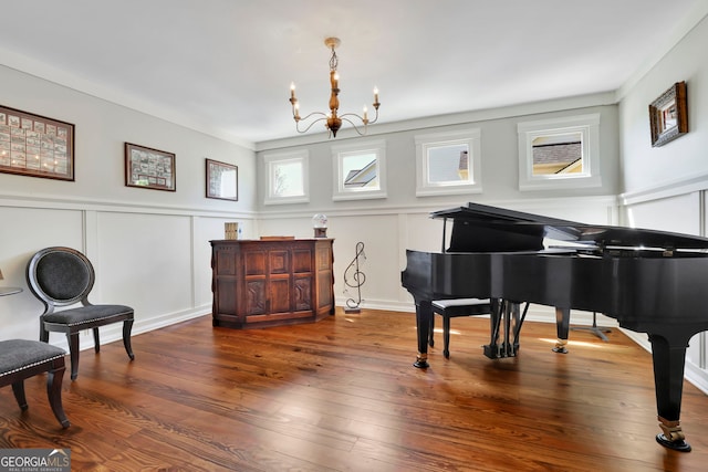 sitting room featuring an inviting chandelier, a wainscoted wall, hardwood / wood-style flooring, and a decorative wall