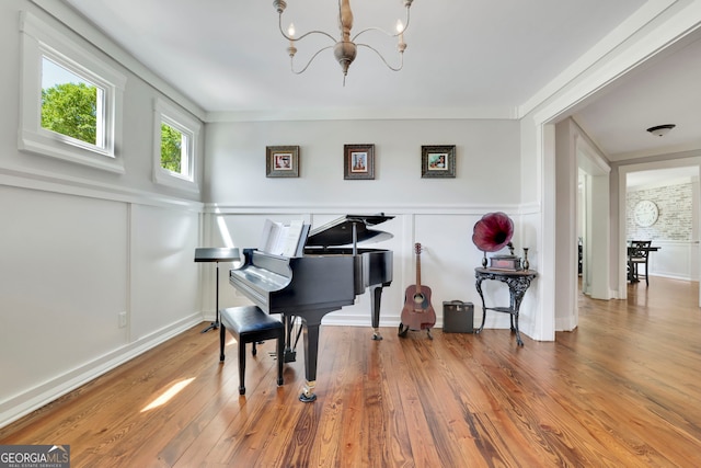 sitting room with a wainscoted wall, a decorative wall, wood finished floors, and a chandelier