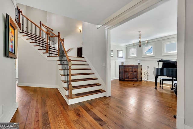stairs featuring visible vents, baseboards, a notable chandelier, and hardwood / wood-style flooring