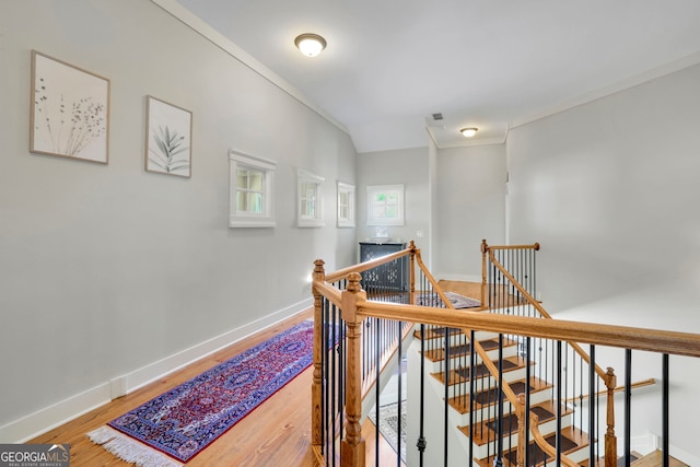 hallway featuring baseboards, wood finished floors, and an upstairs landing