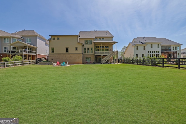 rear view of property featuring a fenced backyard, a yard, and stairway