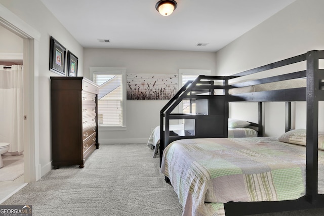 carpeted bedroom with baseboards, connected bathroom, and visible vents