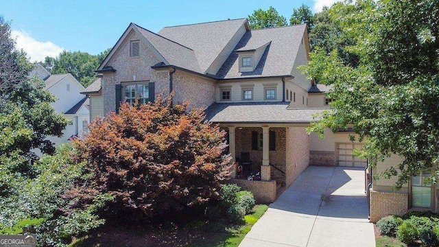 view of front of home featuring a garage, covered porch, a shingled roof, and driveway
