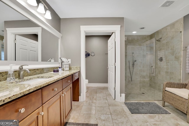 bathroom featuring vanity, toilet, baseboards, a shower stall, and visible vents