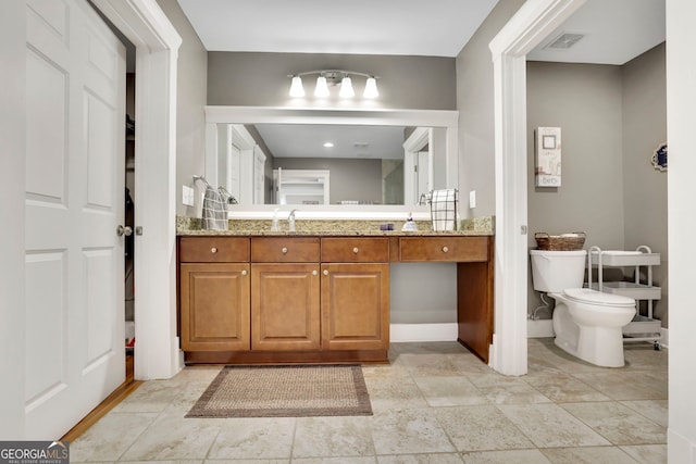 bathroom featuring baseboards, vanity, toilet, and visible vents
