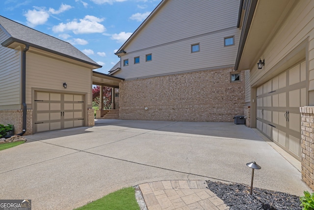 view of property exterior featuring brick siding, driveway, and a garage