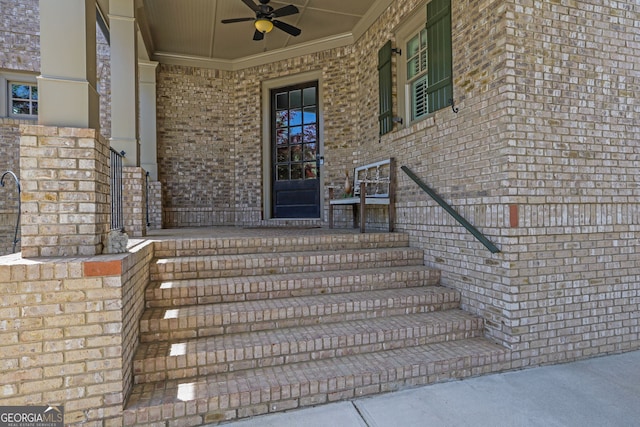 entrance to property with a porch, brick siding, and a ceiling fan
